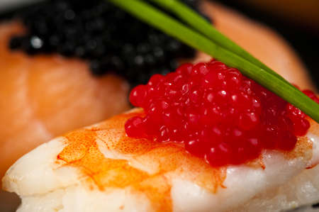 Smoked salmon and prawn nigiri and norimaki sushi garnished with red and black fish eggs and chives. の写真素材