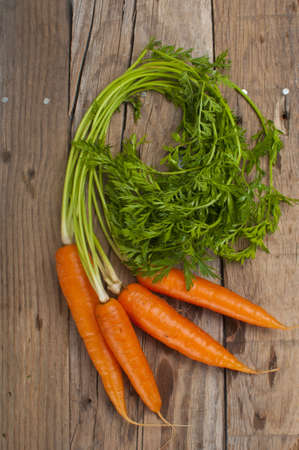 Bunch of four,  fresh crispy carrots on an old wooden boardの写真素材