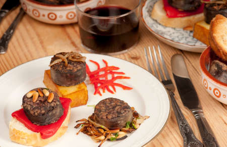 Mixed Spnish tapas with morcilla, pine nuts, confit potato, bread, toast, piquillo pepper, red,...
