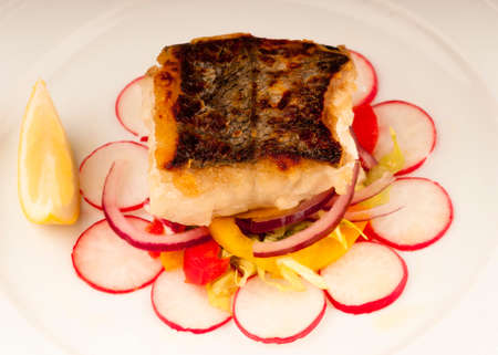 Seared cod fillet with crispy brown skin and accompanied by a salad of red onion, yellow pepper and...