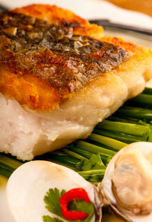 Seared cod fillet with crispy brown skin on a bed of chives in dressed with olive oil and vinegar. ...
