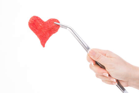 female hand hold a red heart with a tweezerの写真素材