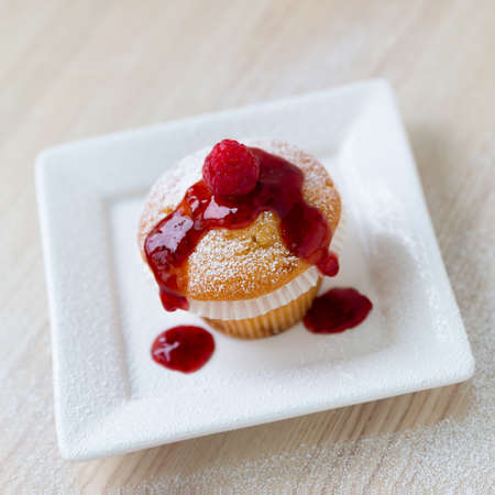 Muffin with raspberry juice on a white plate