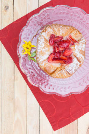 strawberry cake on a glass plate standing on a red table runner