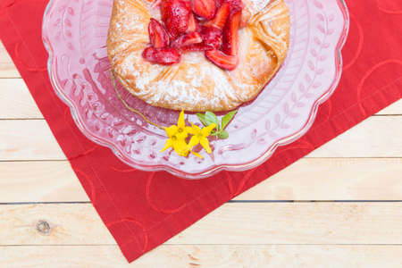 strawberry cake on a glass plate standing on a red table runnerの写真素材