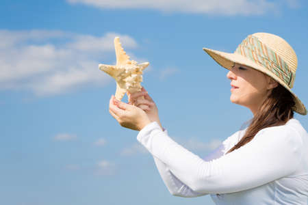 woman against blue sky holding a starfishの写真素材