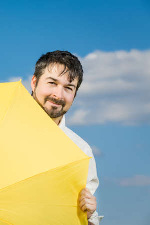 man with a yellow umbrella against blue sky