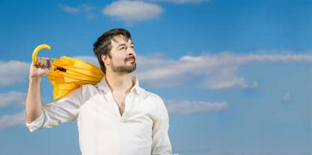 man with a yellow umbrella against blue skyの写真素材