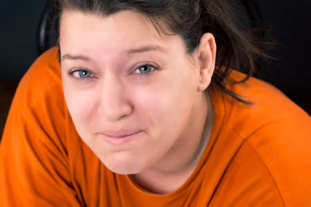 portrait of a woman who is crying wearing a orange shirt