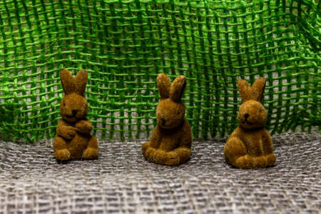 three toy rabbits sitting on a talbein a raw against green linenの写真素材