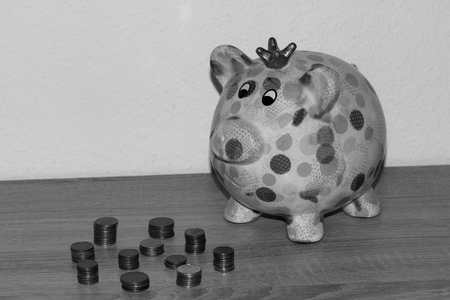view at a piggy bank with steepled cent coins photographed on a wooden underground and white background indoors in black and whiteの写真素材