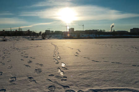 Footprints on a frozen lake in the rays of the sunの写真素材