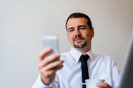 Handsome mid-aged man using mobileの写真素材