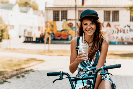 Outdoor lifestyle portrait of pretty young girl sitting on street bicycleの写真素材