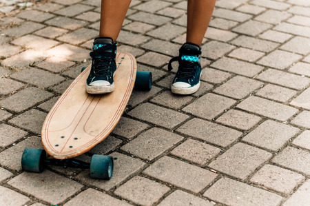 Girl's leg in sneakers standing on a skateboard.の写真素材