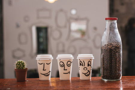 Paper cup of happy takeaway coffee on table.の写真素材