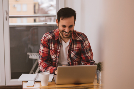 Happy man using laptop computer in officeの写真素材