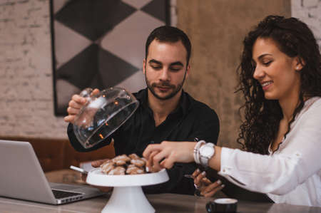 Young couple eating cookies in cafeの写真素材