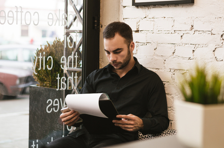 Handsome bar manager checking reports in modern interiorの写真素材