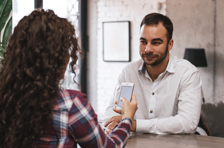 Woman looking at smartphone while on date with guyの写真素材