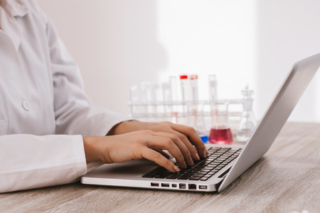 Scientist typing documents into laptop in the laboratory.の写真素材
