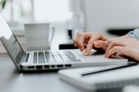 Close up image of woman's hand working on laptop in office.の写真素材