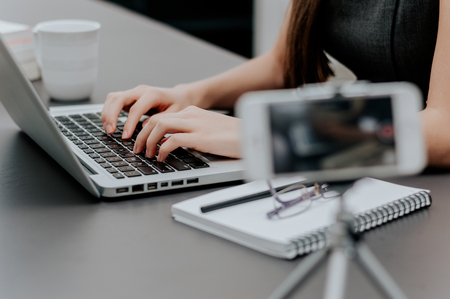 Recording video in office while typing on laptop. Vlog video recording.の写真素材