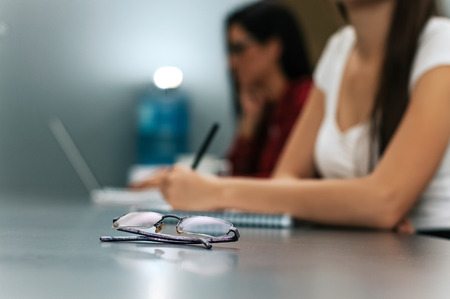 Glasses on table, businesswomen in background. Business concept.の写真素材