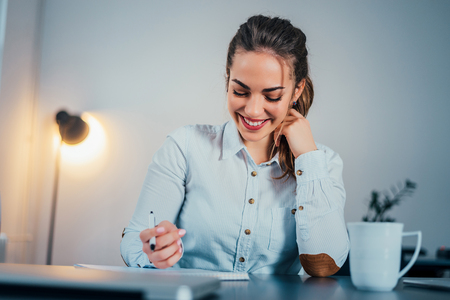 Young female is writing notes and planning her scheduleの写真素材