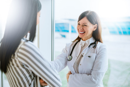 Cheerful doctor talking with her patient near window.の写真素材