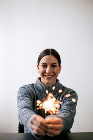 Smiling woman holding sparkles. Looking at camera.の写真素材