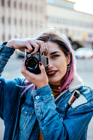 Portrait of a beautiful photographer girl in denim jacket at city street.の写真素材