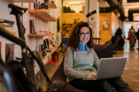 Cute woman with laptop in modern workplace.