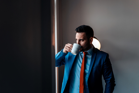 Taking a break. Businessman drinking coffee near the window.の写真素材