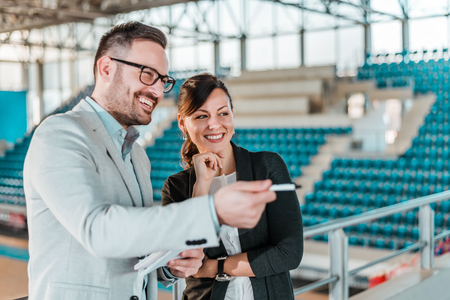 Meeting in a sport hall. Organizing a sport event. Business men and woman in a sport stadium.の写真素材