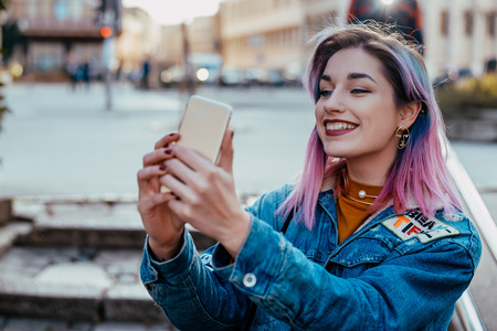 Smiling hipster girl taking selfie at city street.のeditorial素材