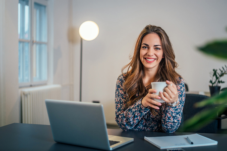 Portrait of attractive woman in office holding cup of coffee.の写真素材