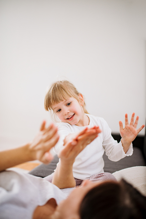 Happy little girl and her mother playing at home.の写真素材