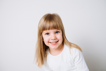 Portrait of a blonde little girl on white background.の写真素材