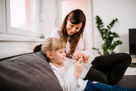 Mother and daughter playing games on smartphone.の写真素材