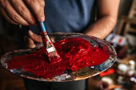 Artist holding palette with red color. Close-upの写真素材