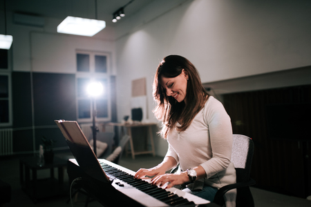 Female composer playing synthesizer pianoの写真素材