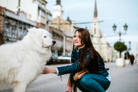 Young woman cuddling a dog on the city street.の写真素材