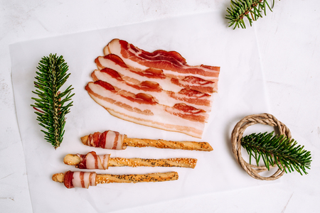 Top view of sliced bacon wrapped around pretzels on white background.の写真素材