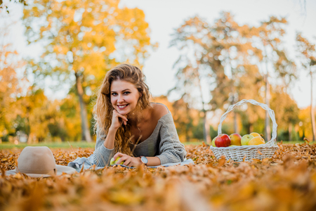 Young fashion woman laying on grass in autumn park.の写真素材