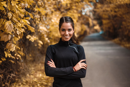 Portrait of female athlete in autumn park.の写真素材