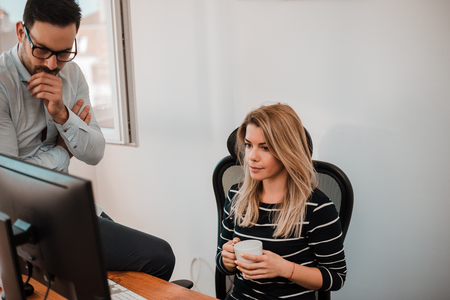 Two concentrated  business people in office looking at monitor.の写真素材