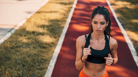 Portrait of attractive brunette female runner running in city park.の写真素材