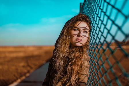Portrait of young woman standing at the wire fence.の写真素材