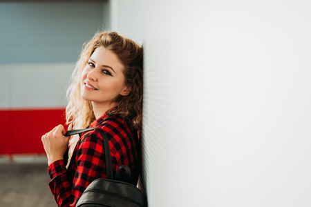 Young beautiful woman with backpack leaning on wall.の写真素材